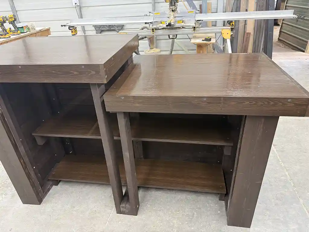 6' Espresso Coffee Shop Sales Counter with ADA drop right & two 11 shelves 5 Two dark brown wooden workbenches with open shelves underneath, in a workshop with tools on a nearby table.